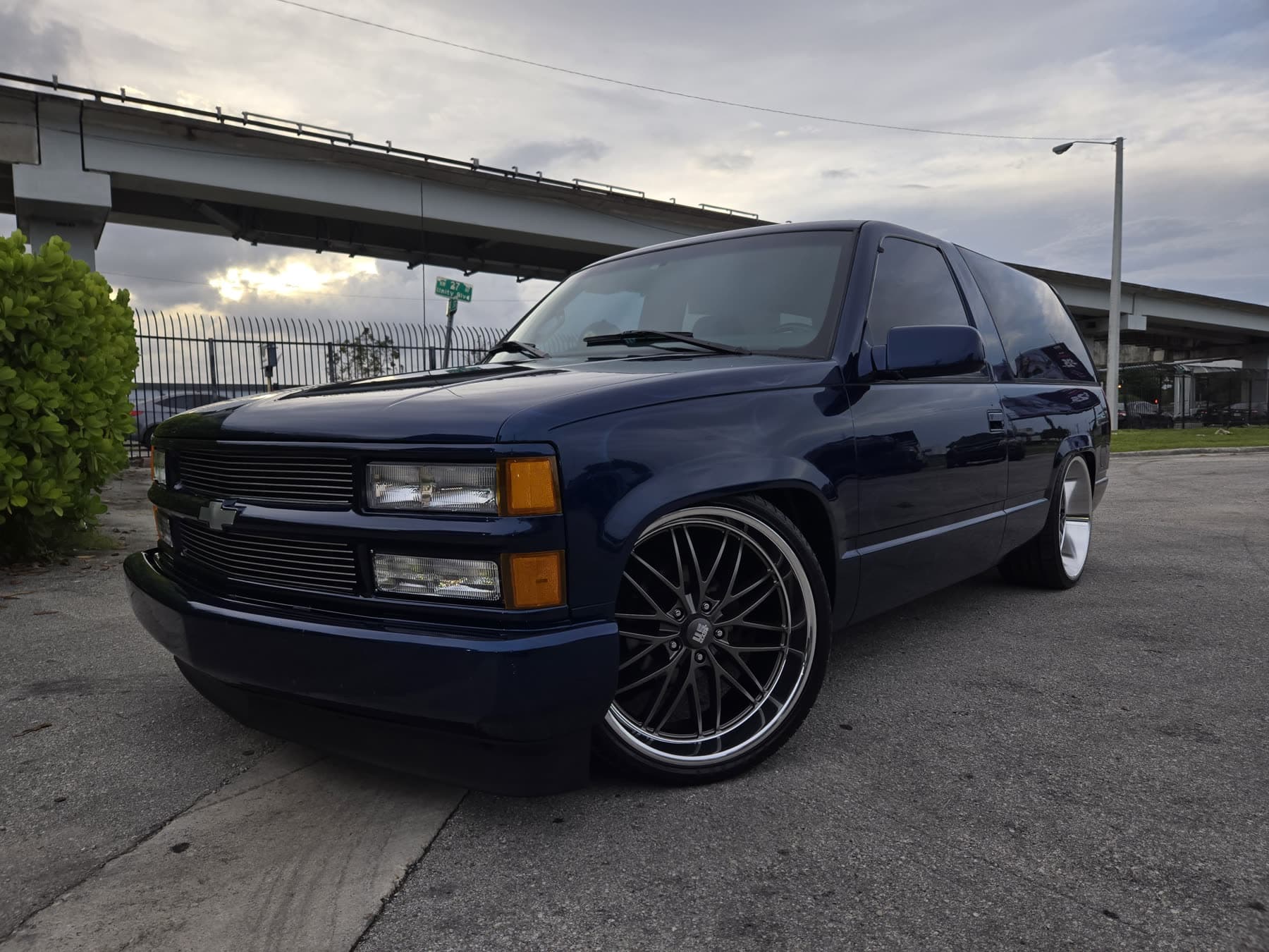 Black lowered Chevy Suburban front three-quarter view with custom wheels