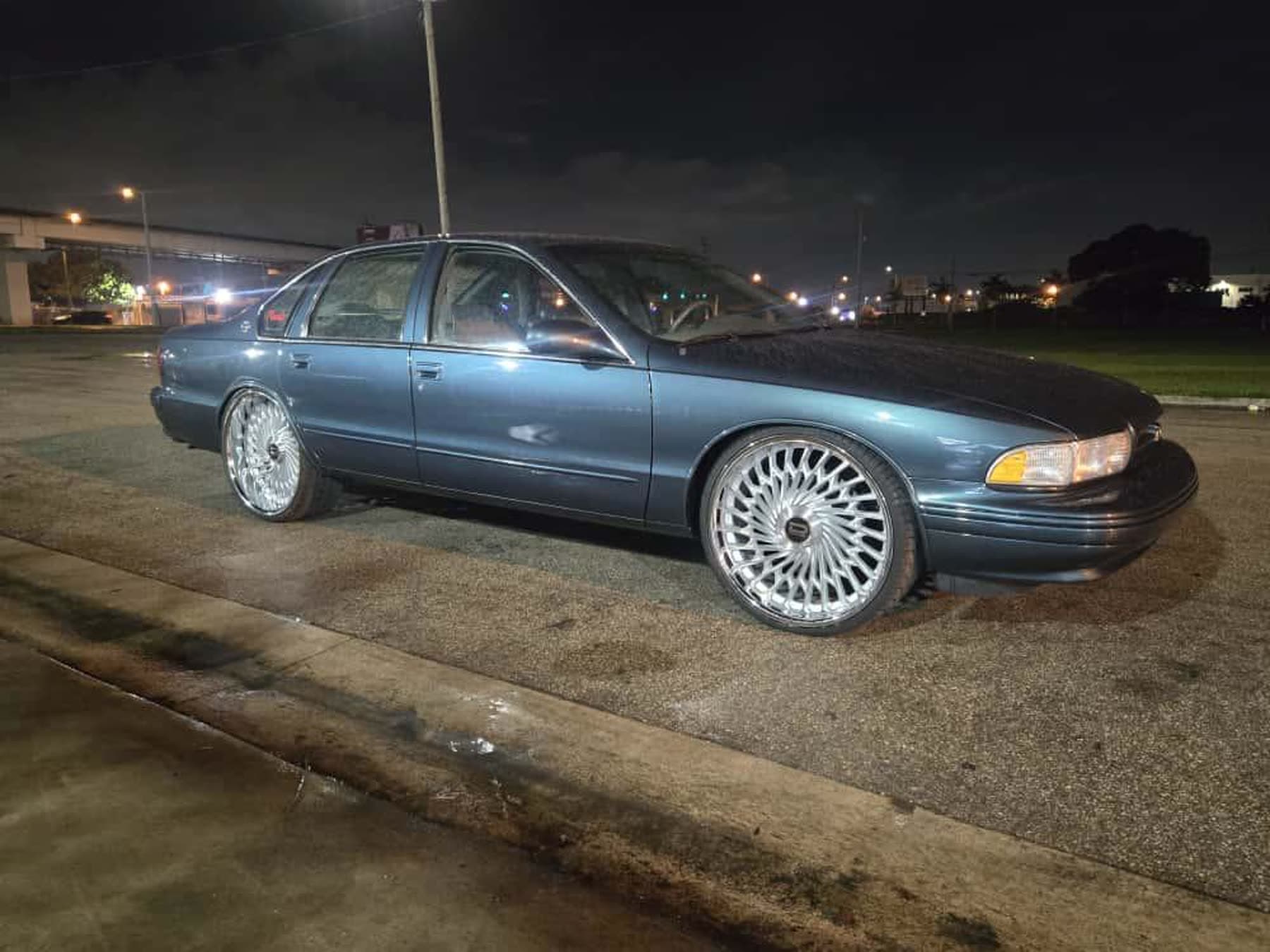 Blue classic Chevy-style sedan at night with polished wheels