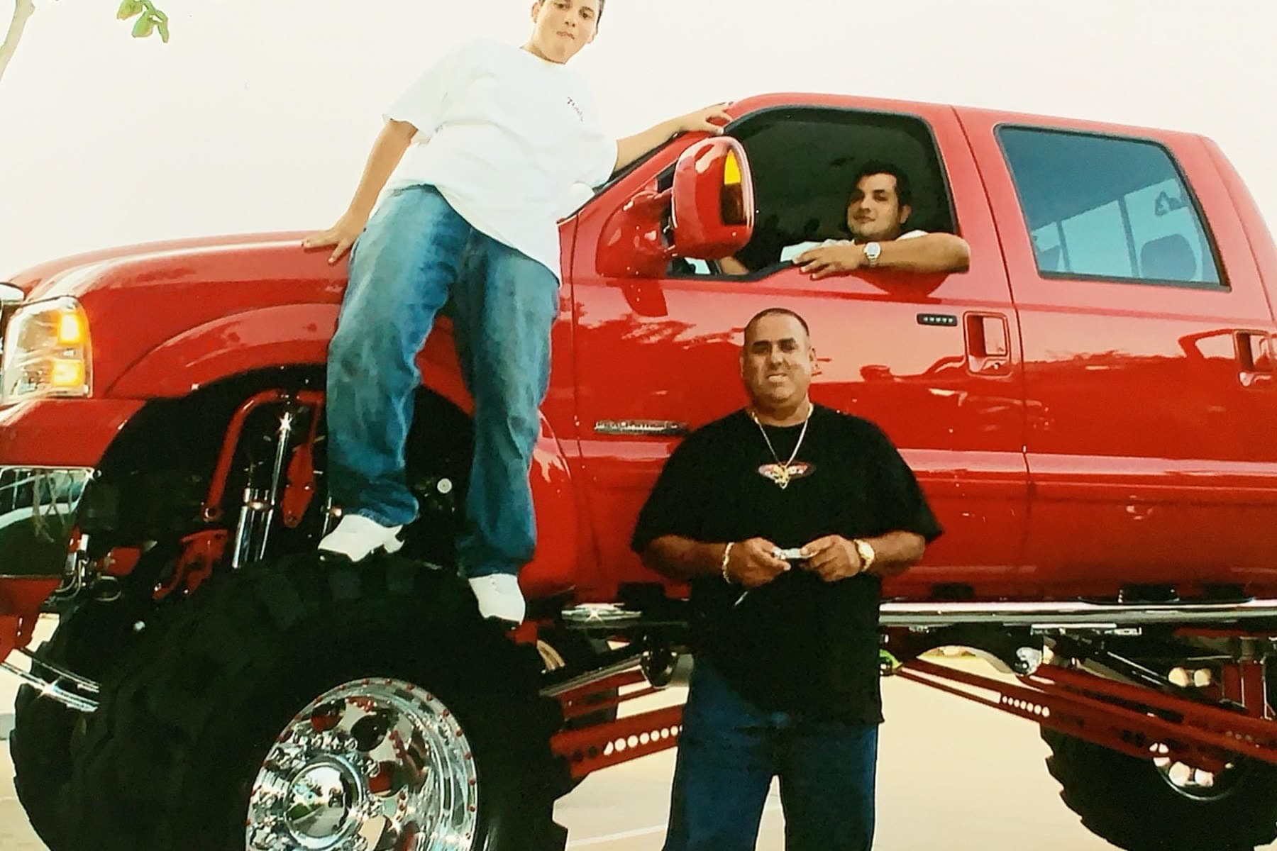 Red lifted dually truck with people nearby at a show