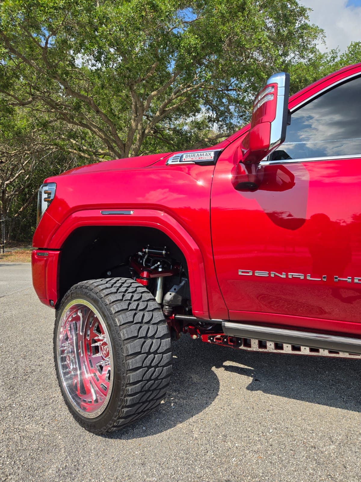 Close view of the custom forged front wheel and suspension on a red GMC Denali